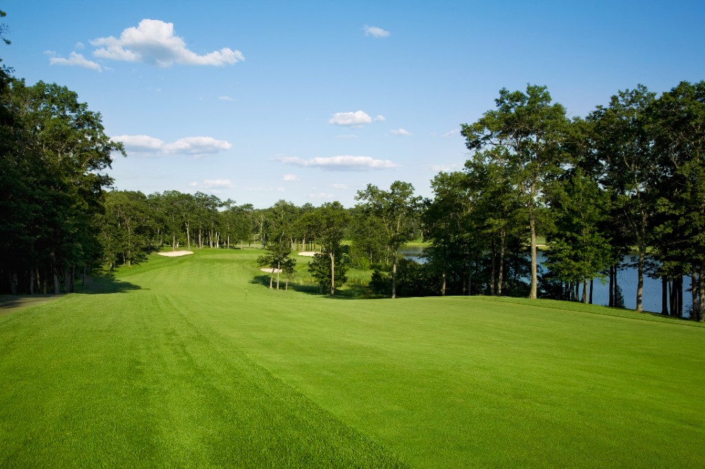 Sunlit golf fairway with bunkers and woodland, golf stays on the Wirral