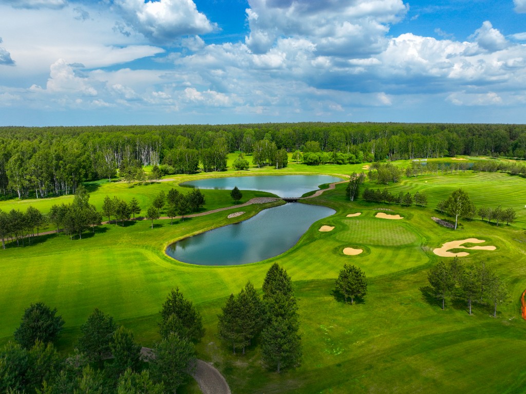 Aerial view of a golf course with lakes, fairways and tree-lined greens